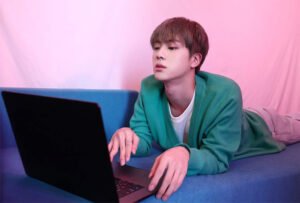 Jin using a laptop cutely