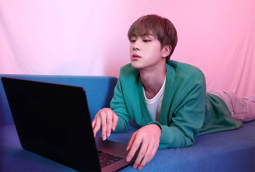 Jin using a laptop cutely